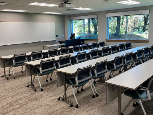 standard classroom of rows of tables and chairs facing the front whiteboard