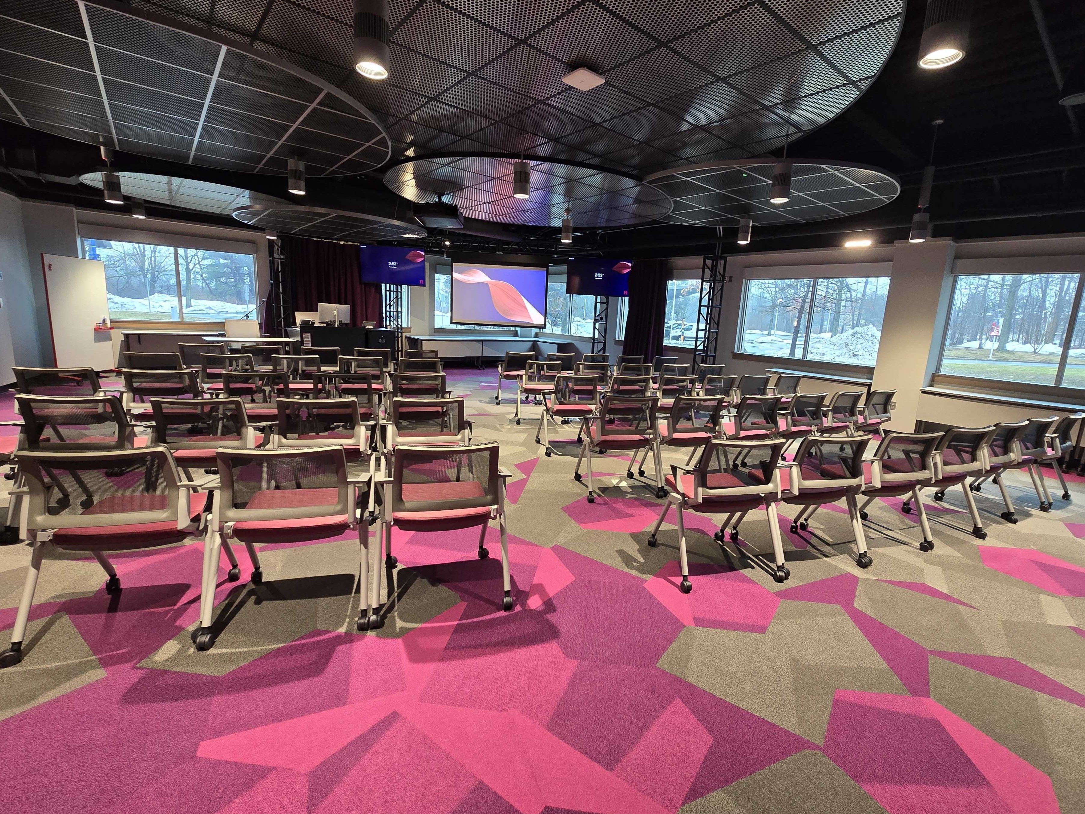 Room in a theater-style layout with rows of chairs facing the front projection screen.