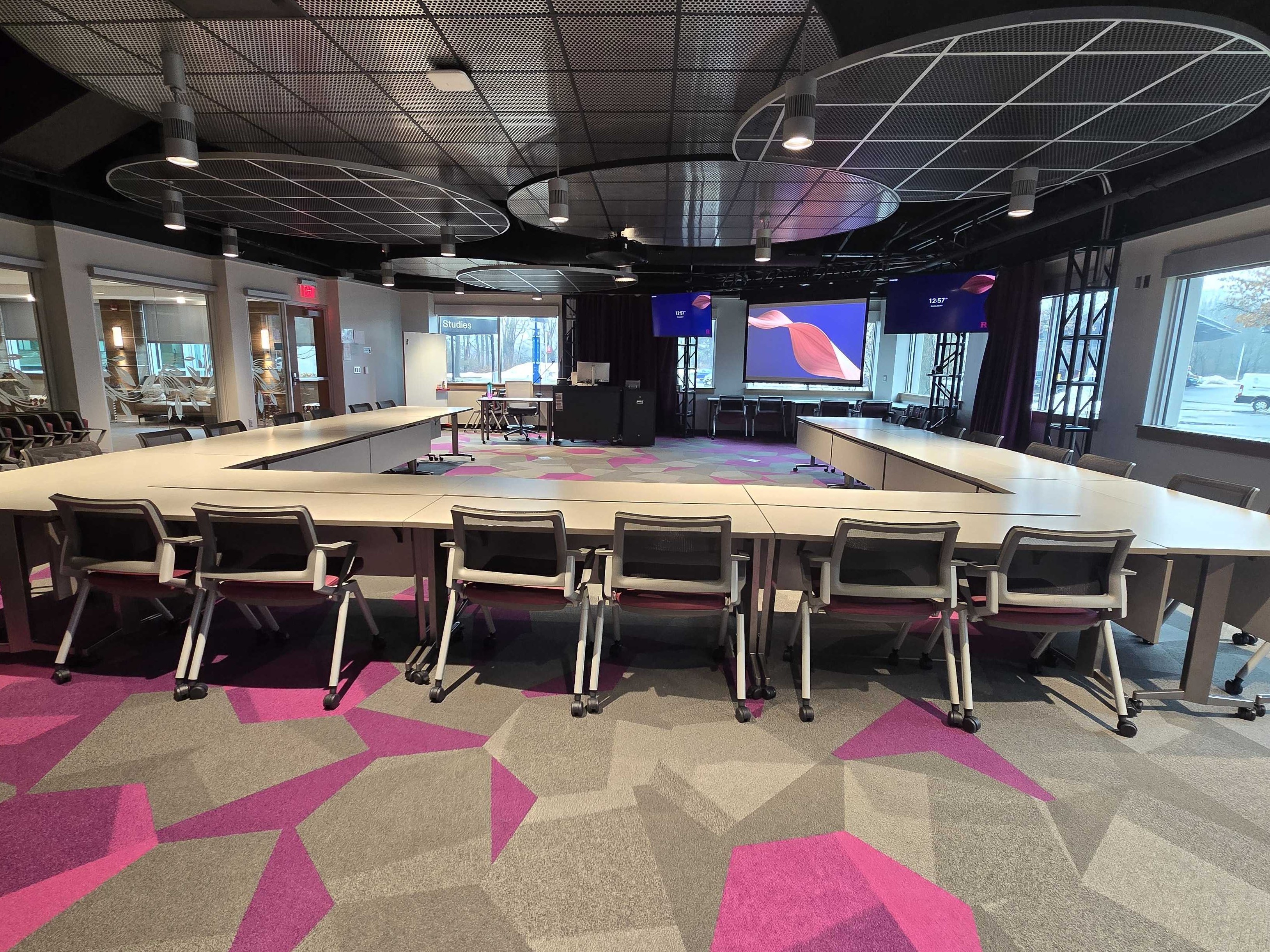 Room in a u-shape layout facing the front projection screen.