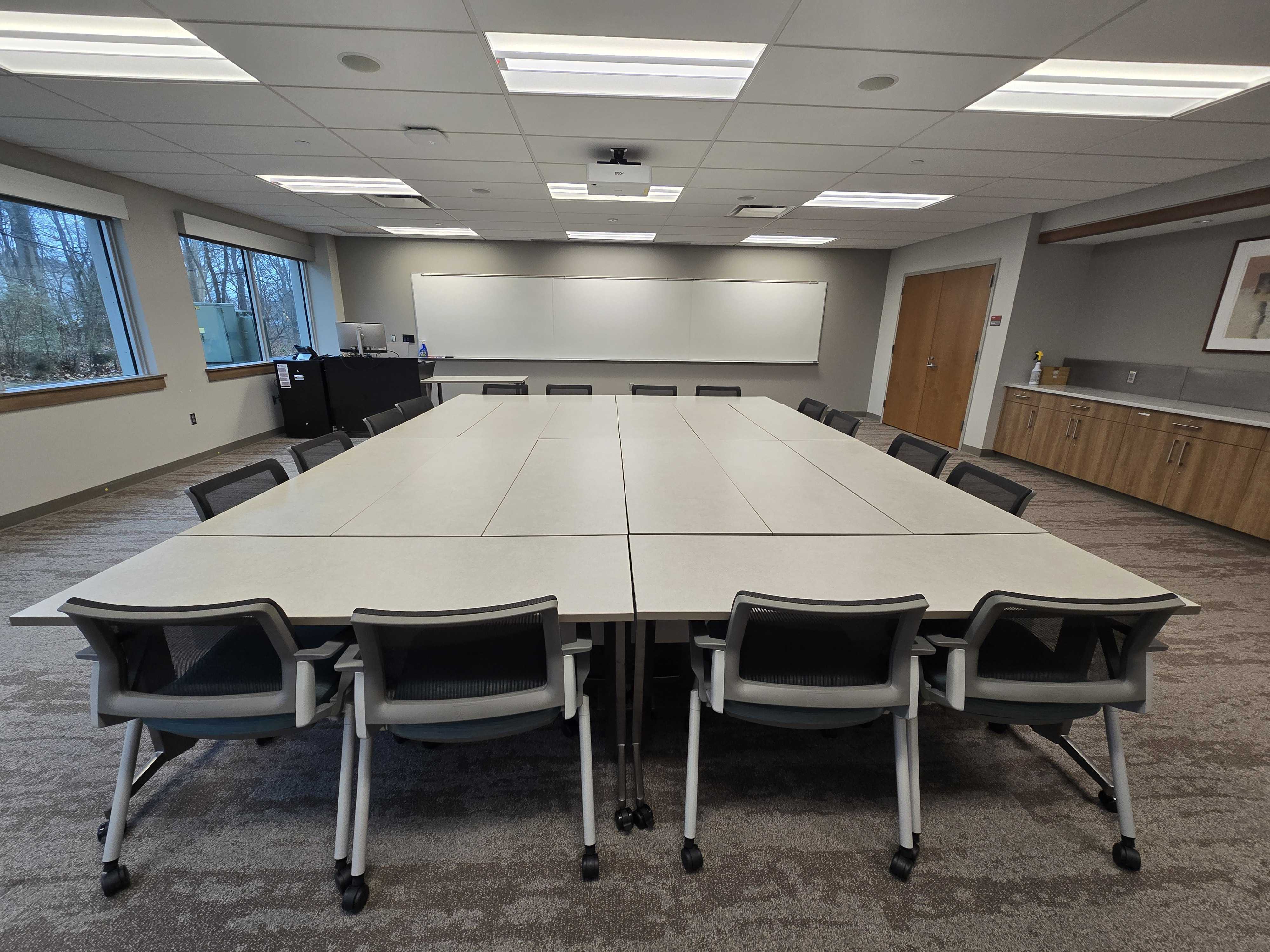 Tables grouped together to form a large conference table with chairs around it. 