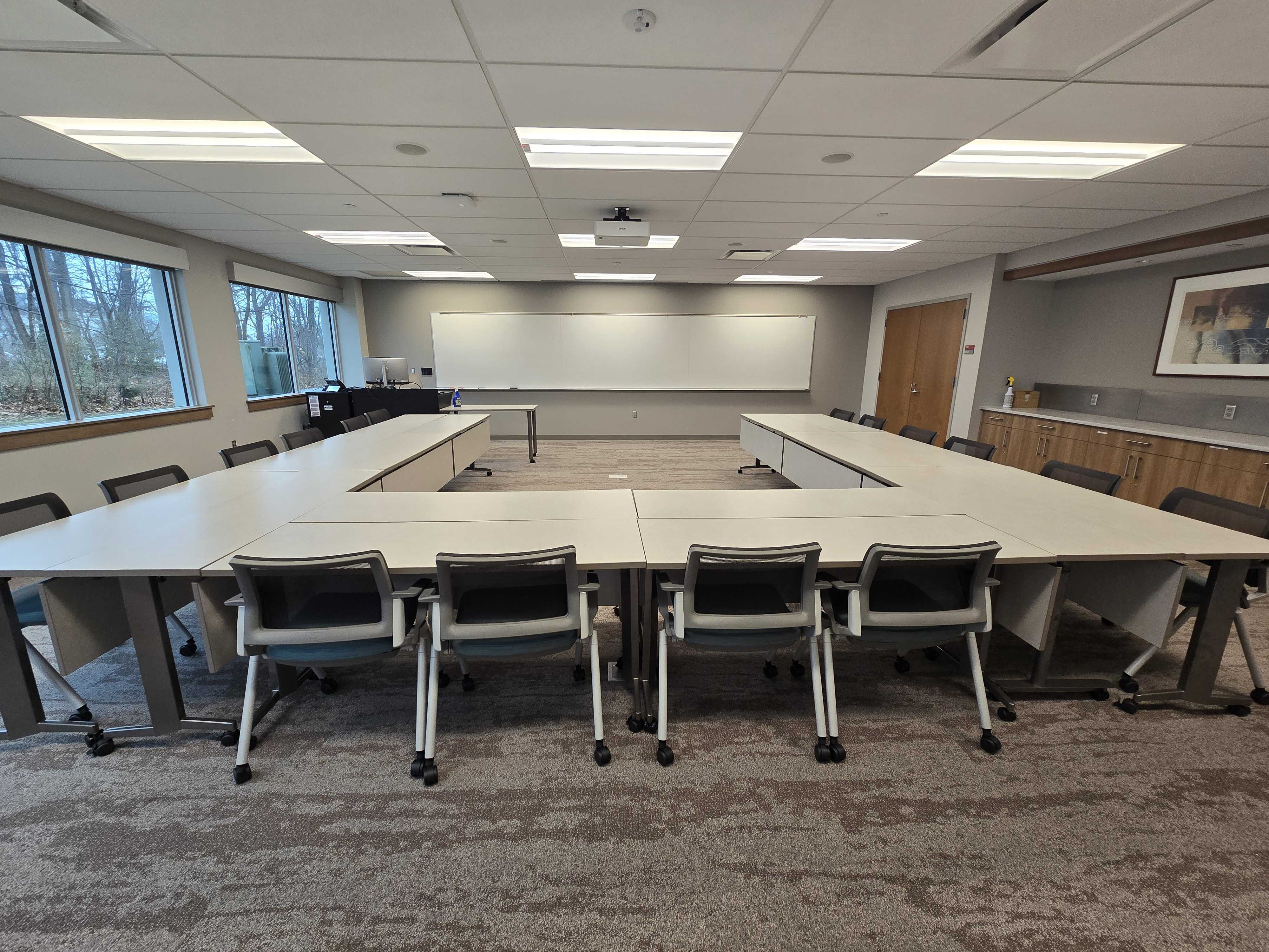 Tables and chairs in a U-shape layout, facing a whiteboard in the front